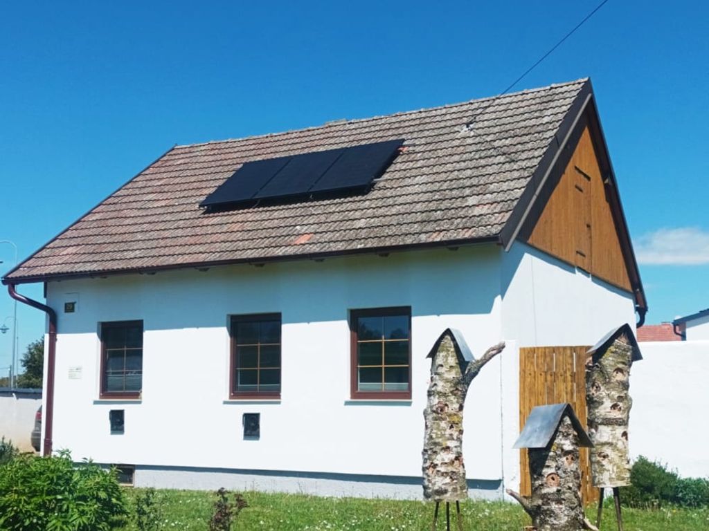 Außenansicht des Ferienhaus mit Solarpaneelen auf dem Dach und Insektenhotels im Garten.