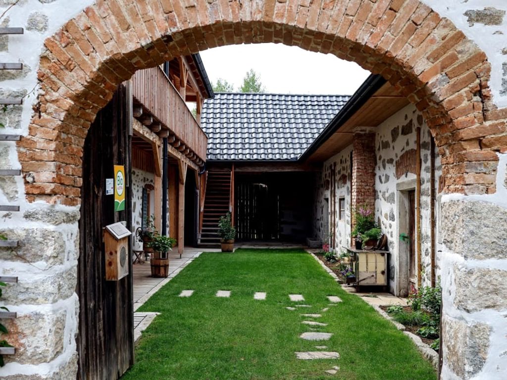 Unser einladender Innenhof, mit historischem Ziegelbogen und charmanter Steinblossfassade.