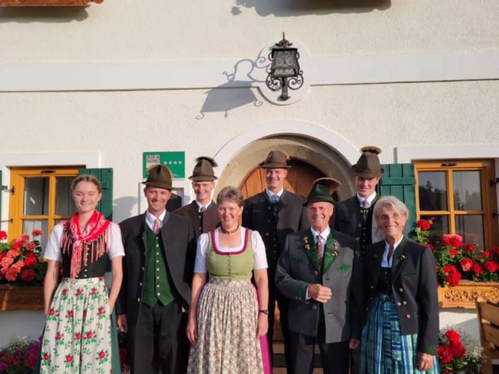 Die Gastgeberfamilie des 4-Sterne-Bauernhofs in traditioneller Tracht vor dem Gebäude.