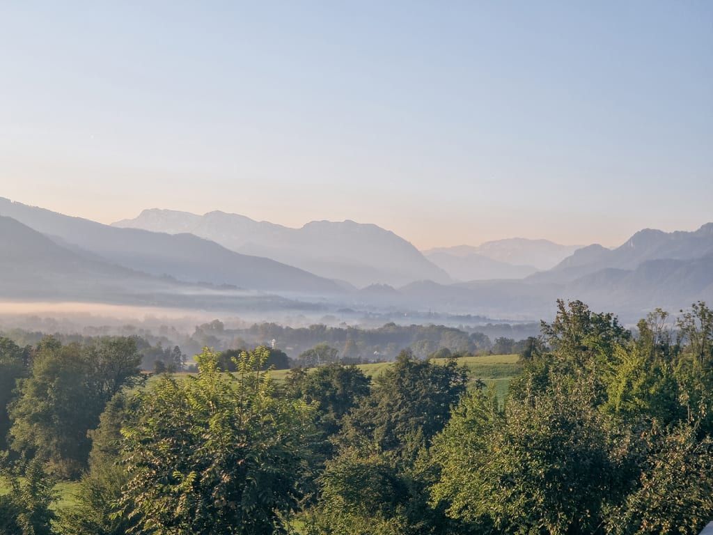 Malerischer Blick vom Hof auf das neblige Alpenvorland am Morgen.