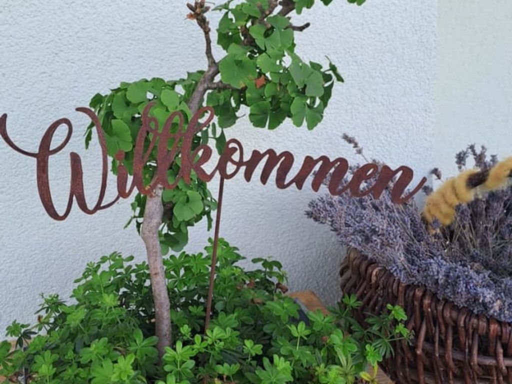 Ein einladendes Willkommensschild inmitten grüner Pflanzen im Eingangsbereich