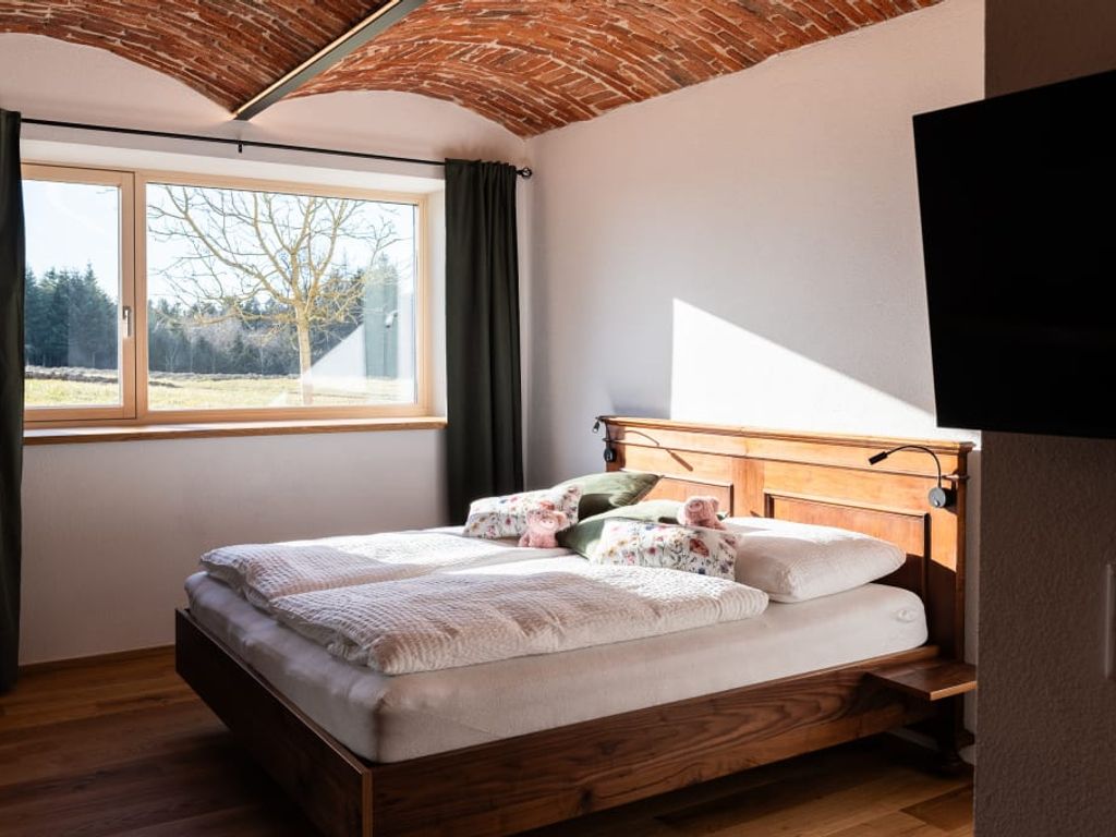 Doppelschlafzimmer im Bauernhof mit Vollholzbett, selbstgenähten Schafwollbetten, gewölbter Backsteindecke, TV und Fenster mit Ausblick.