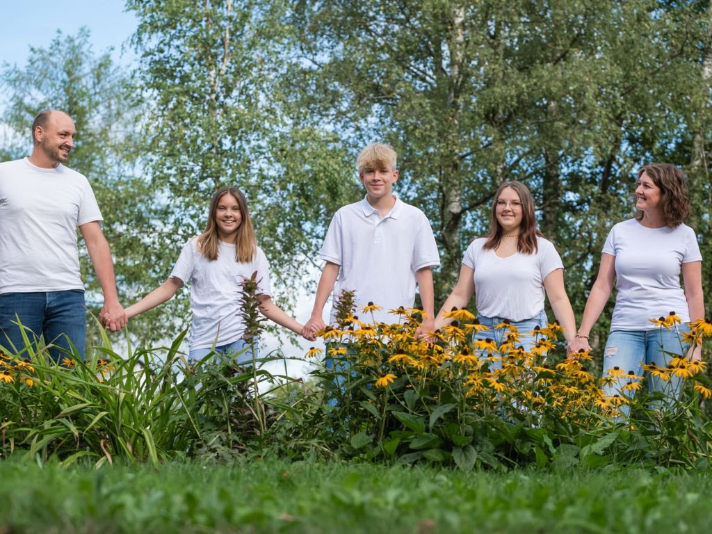Eine Familie mit Kindern steht inmitten von Blumen im Garten des Bauernhofs.