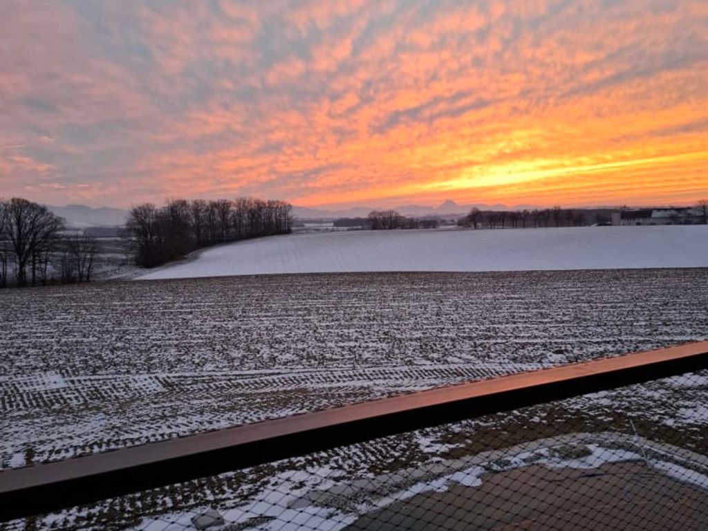 Sonnenuntergang über der verschneiten Landschaft, gesehen vom Balkon des Ferienhauses mit Sicherheitsnetz.