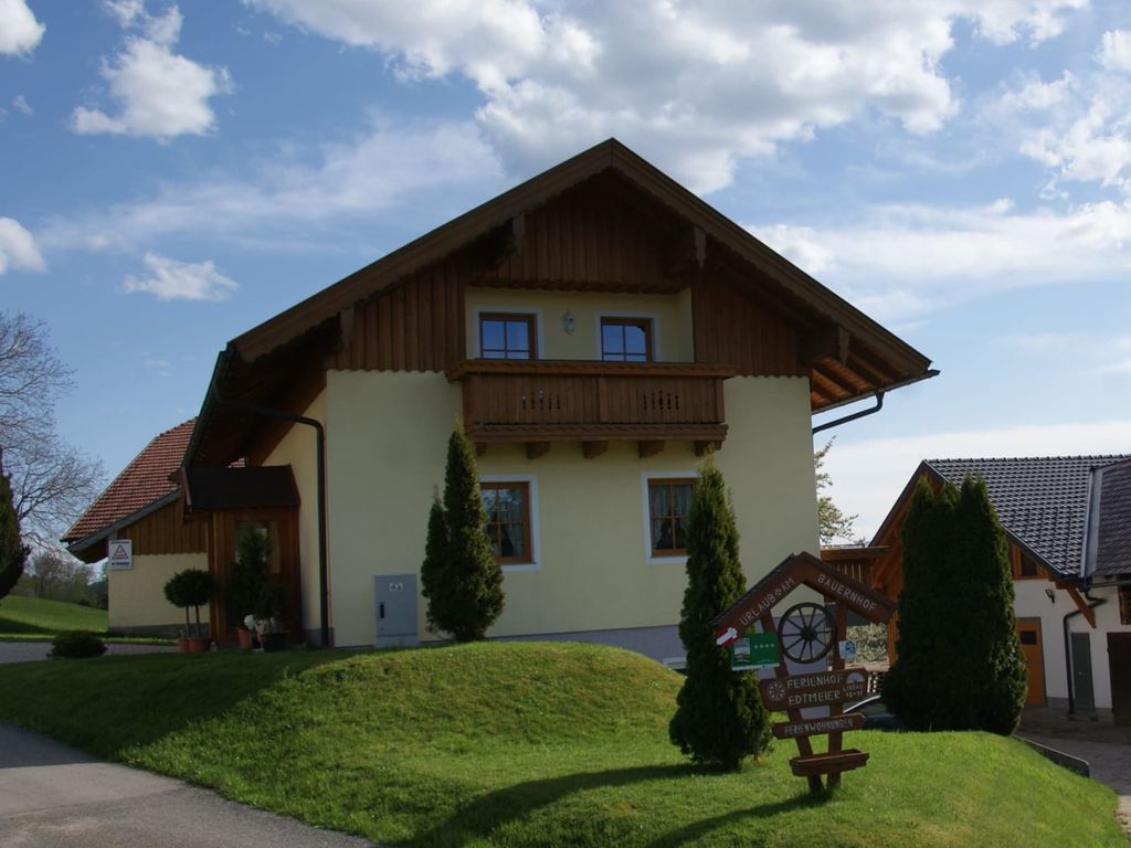 Der Bauernhof von außen mit Balkon und grüner Rasenfläche.
