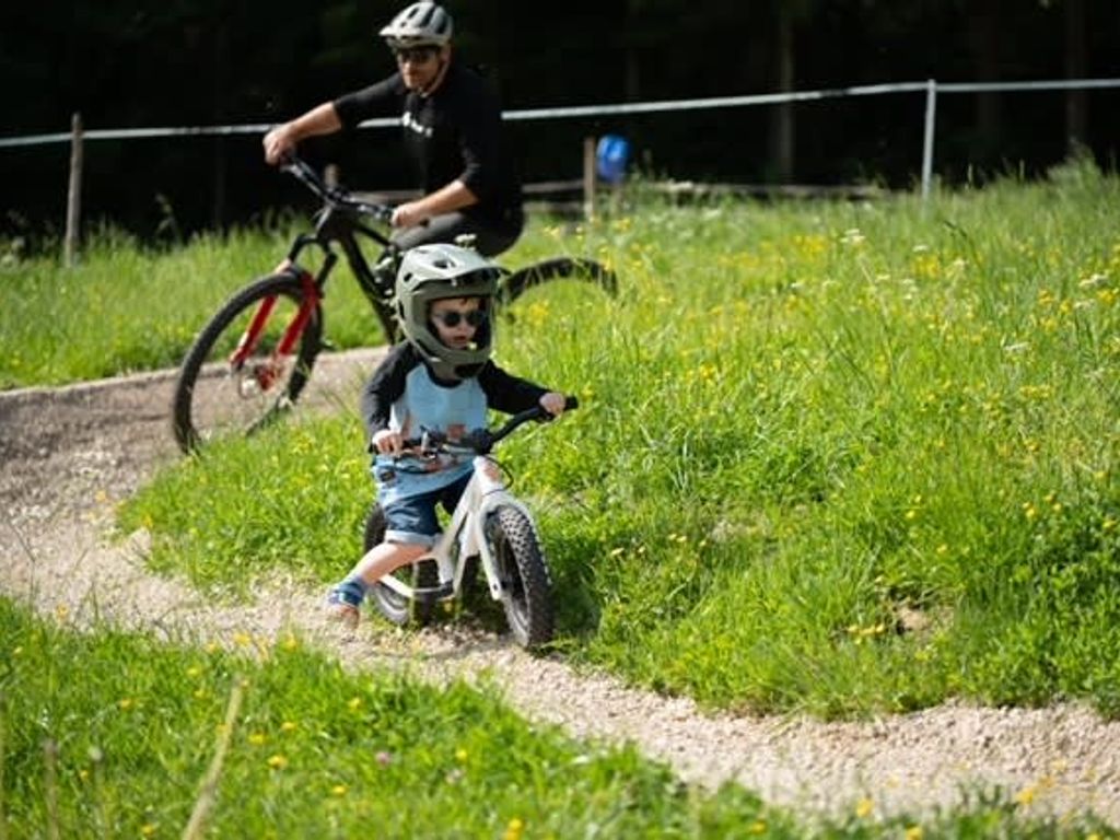 Fahrradfahren für Kinder und Erwachsene auf dem Bauernhof, mit einem Schotterweg und grüner Umgebung.