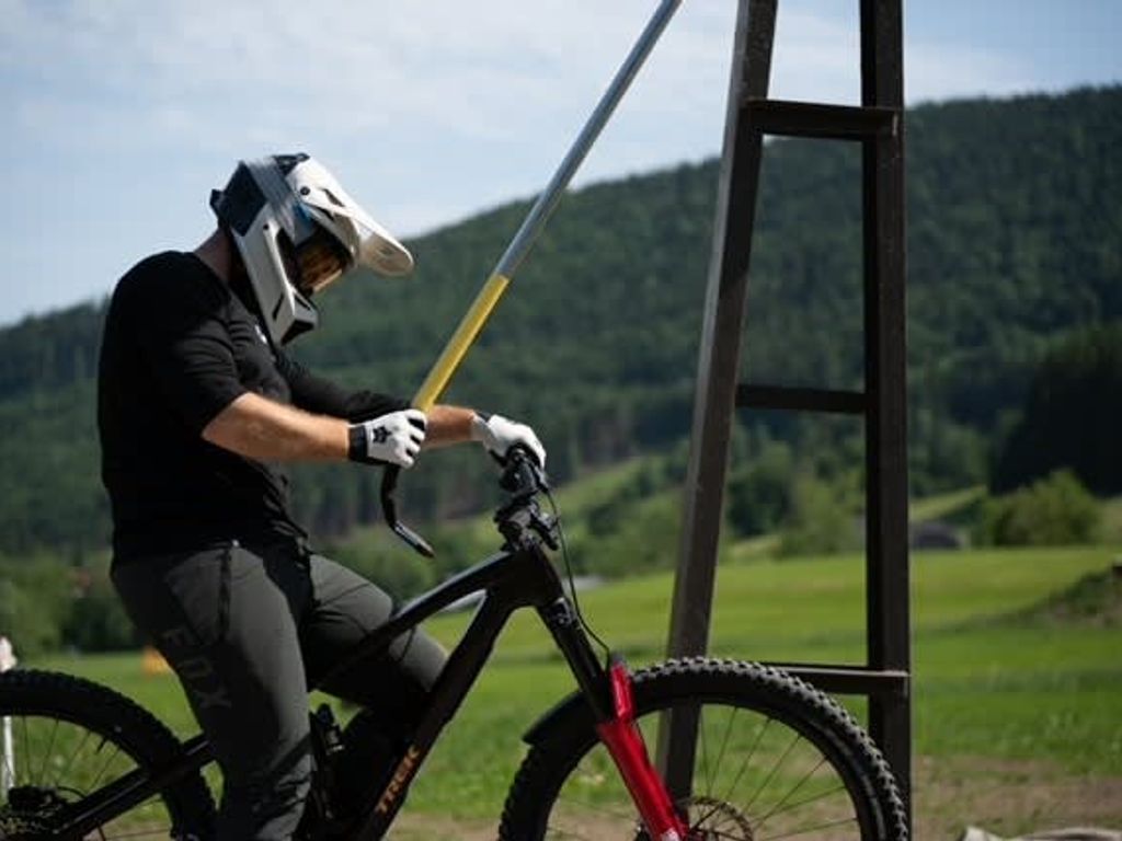 Ein Mountainbiker mit Schutzausrüstung nutzt einen Schlepplift, um die Berge zu erklimmen.