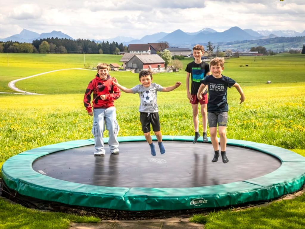 Ein Trampolin für Kinder auf dem Bauernhof mit Blick auf die Berge.