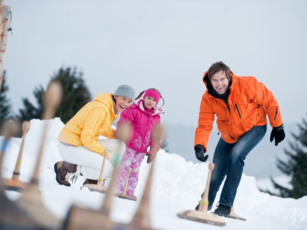 Eisstockschießen im Schnee als winterliches Freizeitangebot für die ganze Familie am Bauernhof.