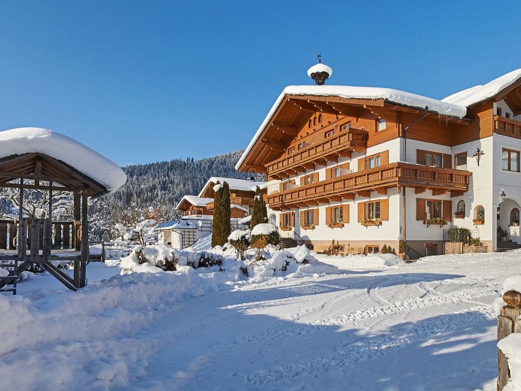Der Bauernhof im Winter mit schneebedeckten Dächern und einem Holzpavillon auf dem Gelände.