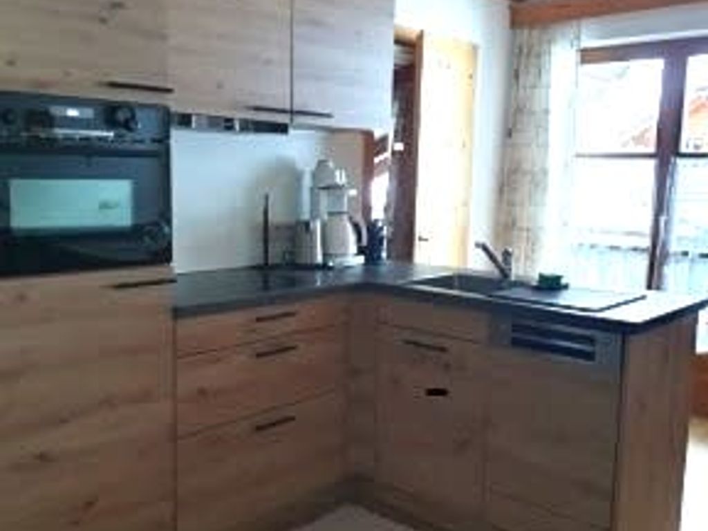 Küche im Bauernhof mit Backofen, Spülmaschine und Holzdecke.