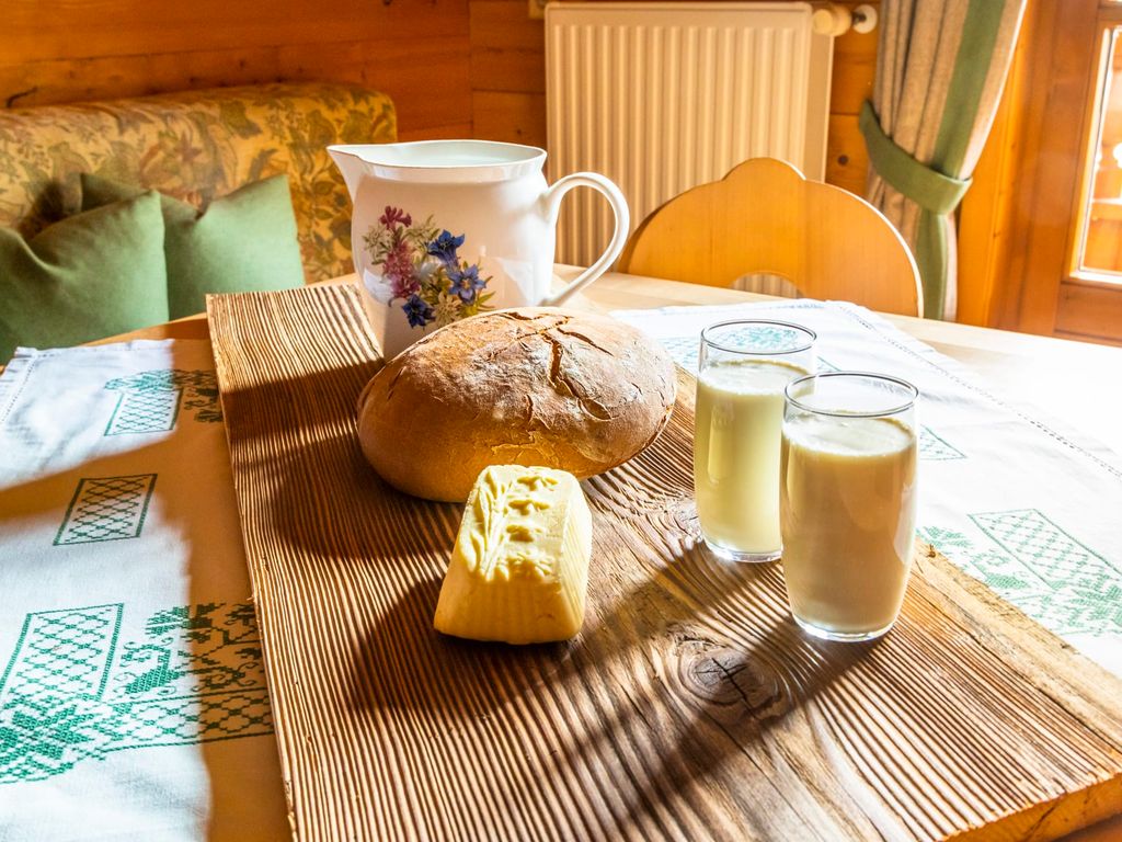 Brot, Butter und Milch auf einem Holzbrett, bereitgestellt für Gäste im Bauernhof.