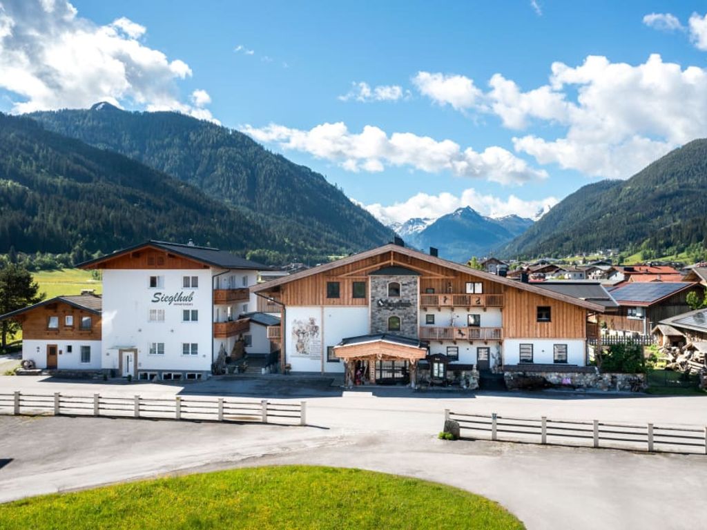 Der Bauernhof Sieglhub mit traditioneller Holz- und Putzfassade, Balkonen und der umliegenden Berglandschaft.