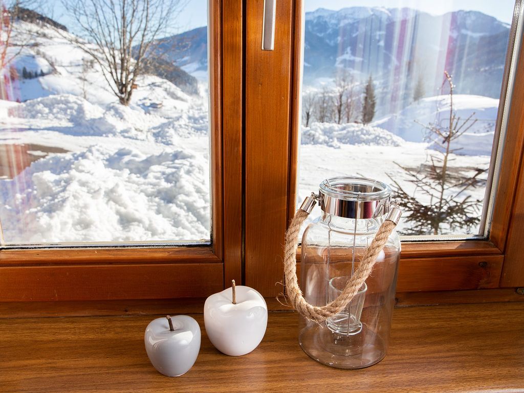 Blick aus dem Fenster des Bauernhofs auf die verschneite Winterlandschaft mit Bergen.