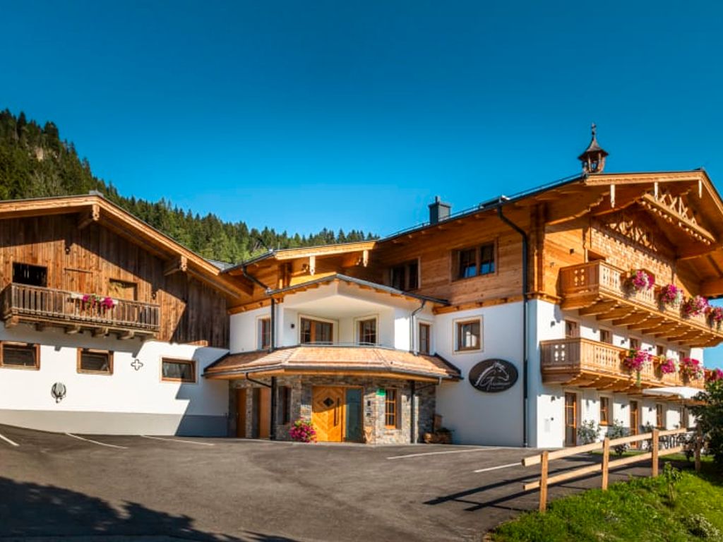 Der einladende Bauernhof mit traditionellen Holzbalkonen vor einer malerischen Bergkulisse.
