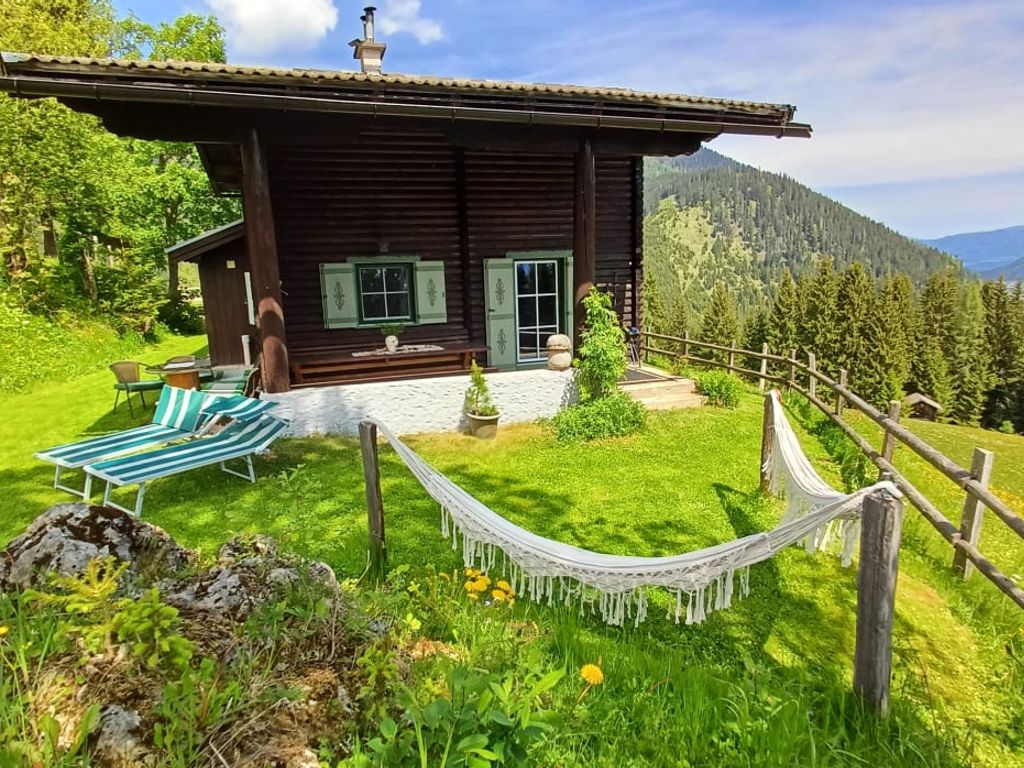 Der Hof mit Rasenfläche, Liegestühlen, Hängematte und einer Berglandschaft im Hintergrund.