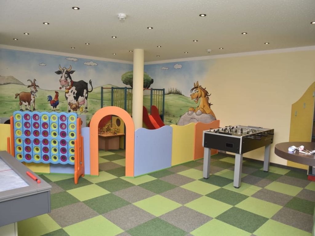 Kinderspielzimmer im Bauernhof mit Bauernhof-Wandmalerei, Tischfußball, Airhockey und verschiedenen Spielgeräten.