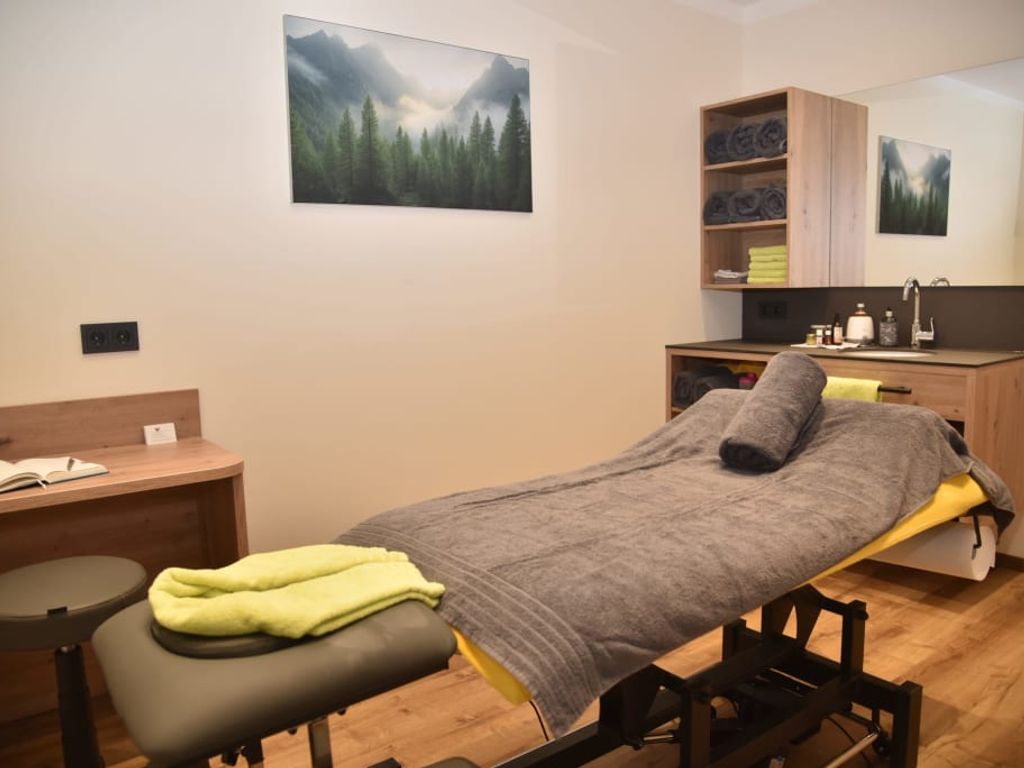 Der Wellnessbereich des Bauernhofs mit einer Behandlungsliege, Waschbecken und frischen Handtüchern.