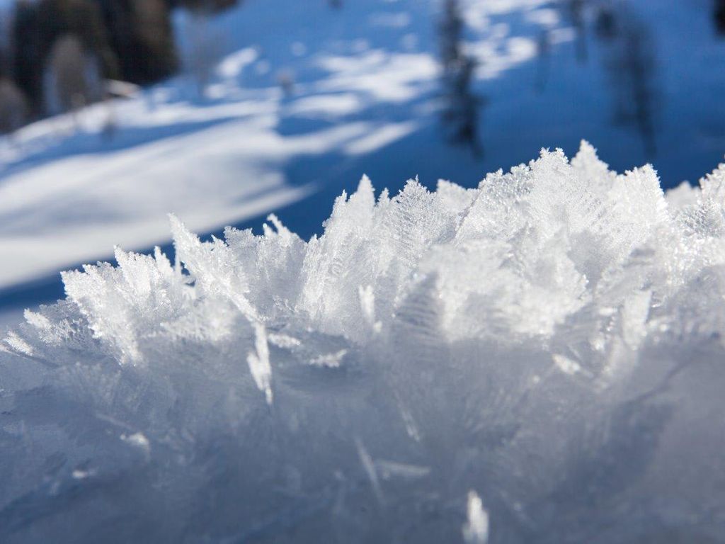 Detaillierte Eiskristalle auf Schnee, die die winterliche Natur rund um den Bauernhof in der Nationalparkregion Hohe Tauern zeigen.