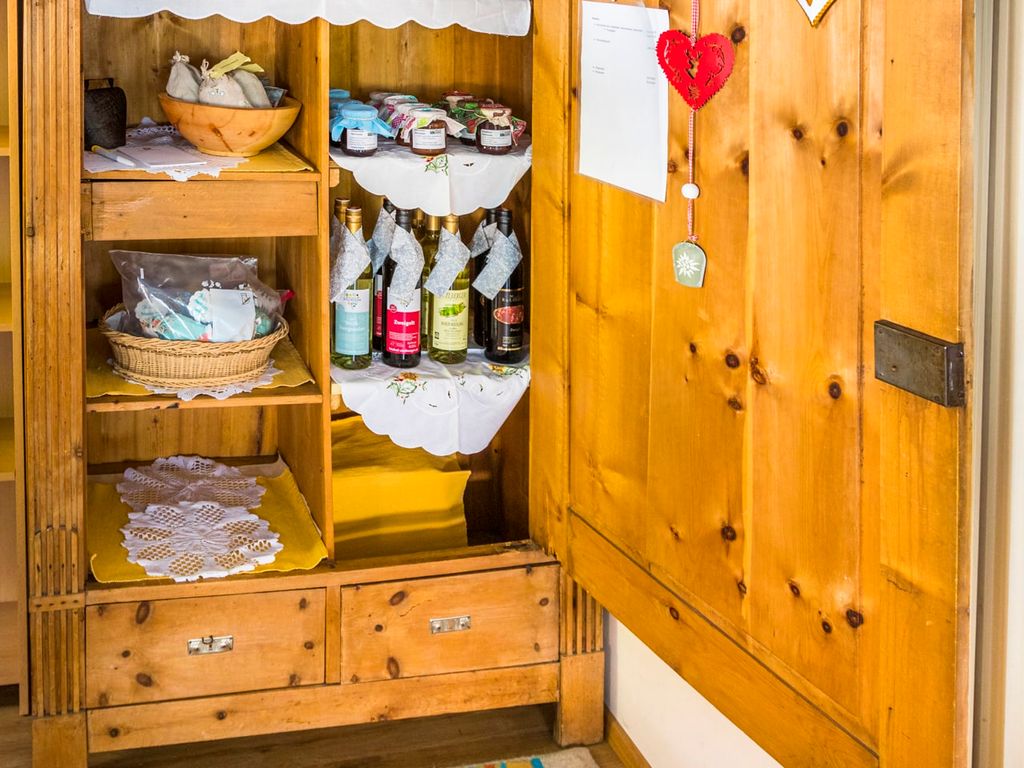 Der Bauernhof bietet eine Auswahl an hofeigenen Produkten wie Marmeladen und Getränke in einem Holzschrank für Gäste an.