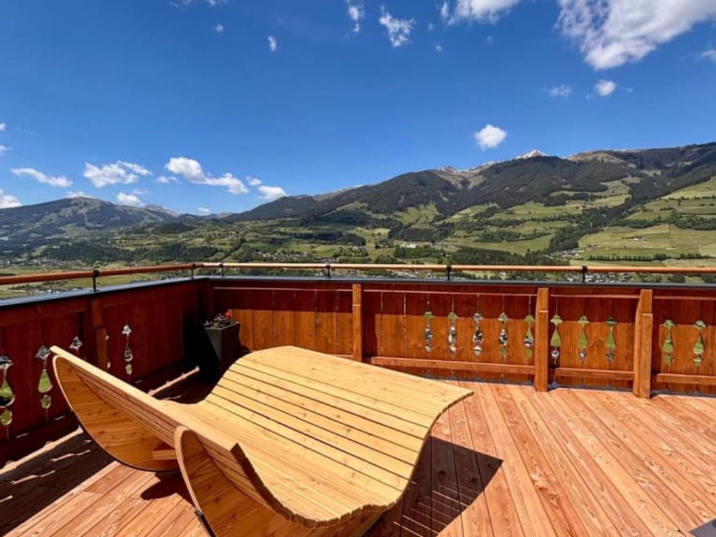 Große Liegeterrasse des Bauernhofs mit gemütlichen Holzliegen und Blick auf die Berge und das Salzachtal.