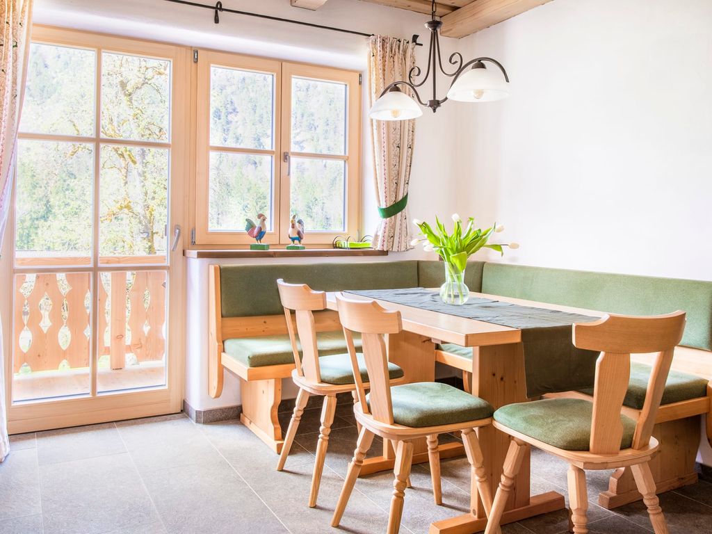 Der Essbereich in der Ferienwohnung auf dem Bauernhof bietet eine Eckbank mit Holztisch und direkten Zugang zum Balkon.