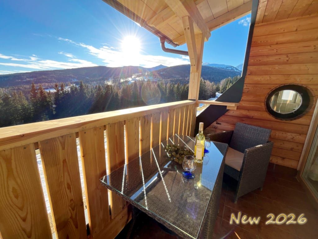 Sonniger Balkon der Grosserhütte mit weitem Blick auf die bewaldete Berglandschaft.