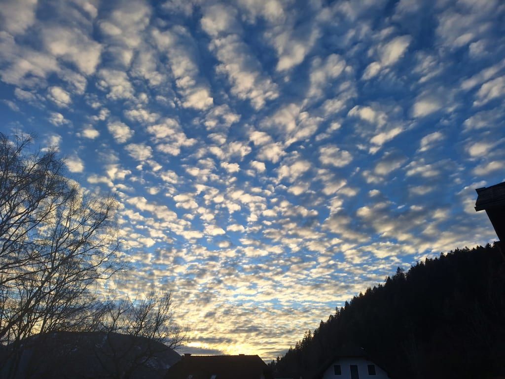 Himmel mit Wolkenmuster über der bewaldeten Umgebung des Bauernhofs.