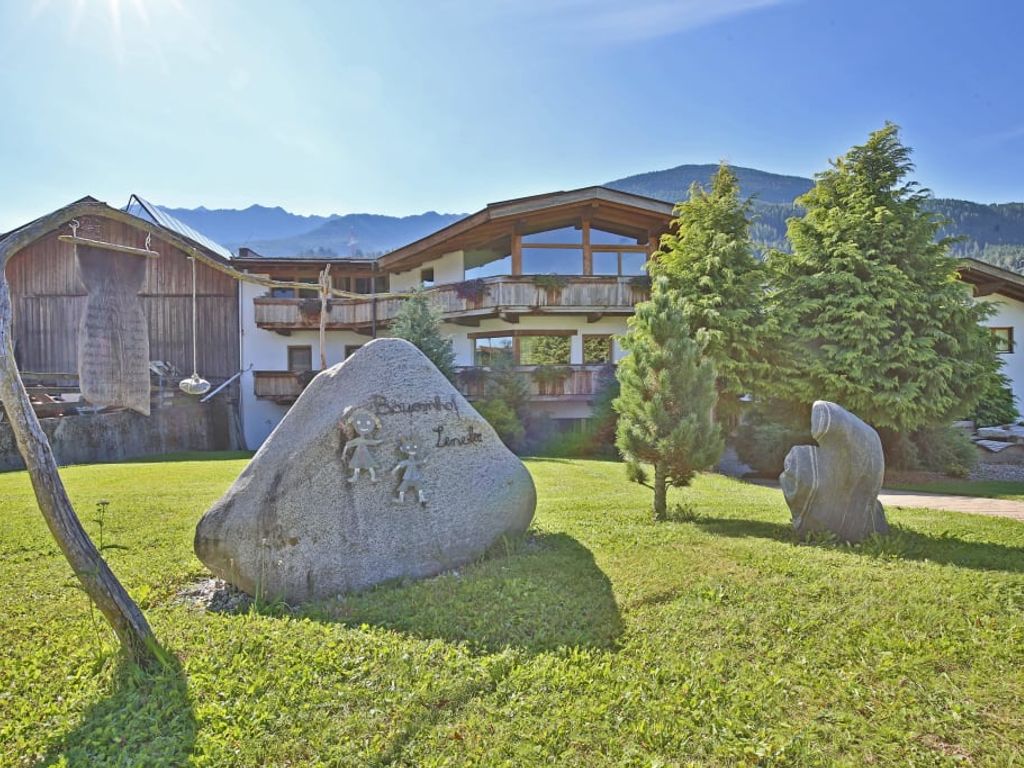 Außenansicht des Bauernhofs Leneler mit Rasenfläche und dem beschrifteten Stein.