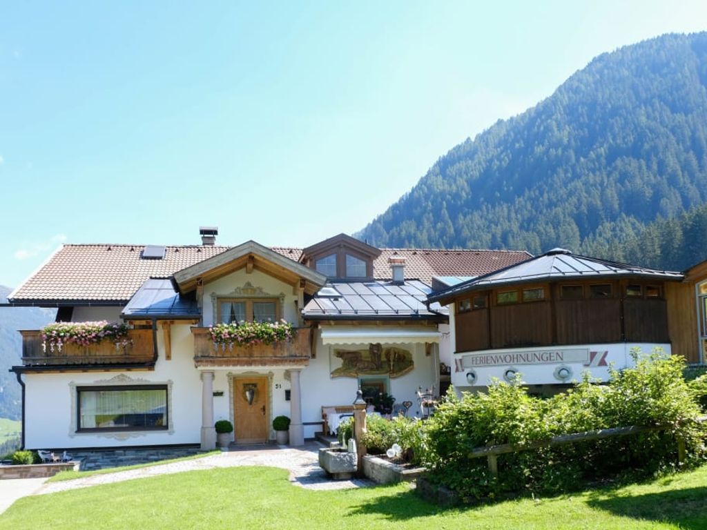 Außenansicht des Bauernhofs mit seinen Ferienwohnungen, Balkonen und der umliegenden Berglandschaft.
