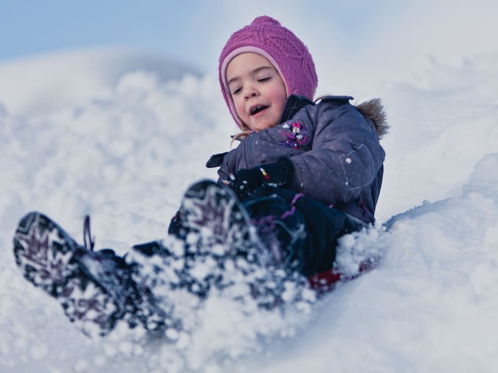Spaß im Schnee, ein Kind rutscht den Schneehügel hinunter