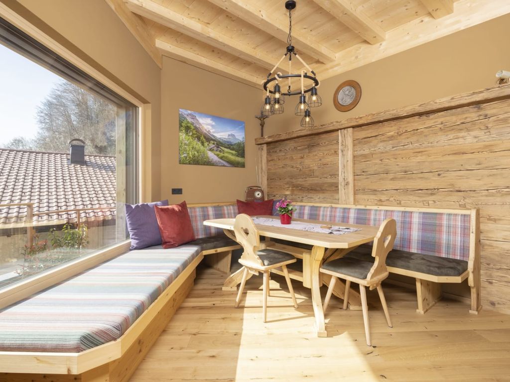 Essbereich im Bauernhof mit Holztisch, Eckbank und einer Sitzgelegenheit an der breiten Fensterfront für viel Tageslicht.
