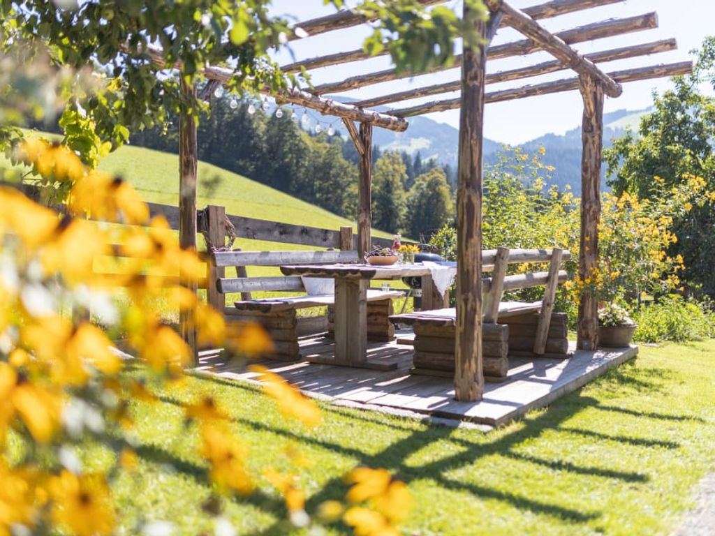 Der überdachte Sitzbereich im Garten des Bauernhofs mit Holztisch und Bänken für Mahlzeiten im Freien.