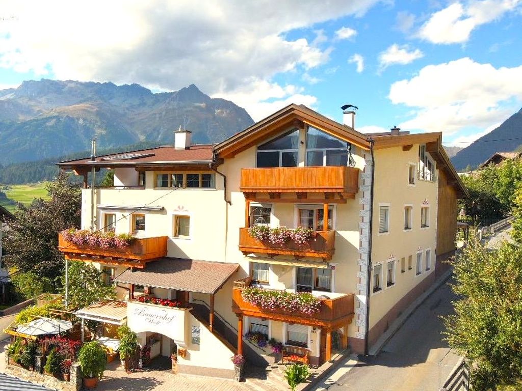 Außenansicht des Bauernhofs mit Balkonen, Blumenkästen, Sonnenterrasse und Bergblick.