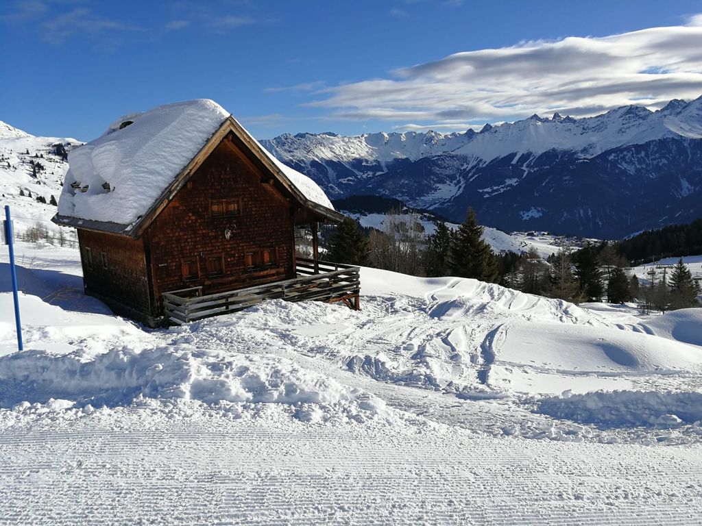 Das verschneite Holzhaus mit Balkon in der winterlichen Berglandschaft des Bauernhofs.