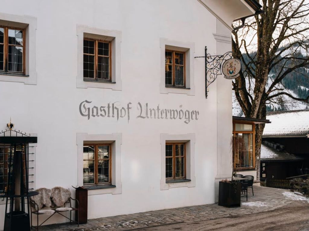 Außenansicht des Gasthof Unterwöger mit Beschriftung, Fenstern und einem Sitzbereich im Freien.