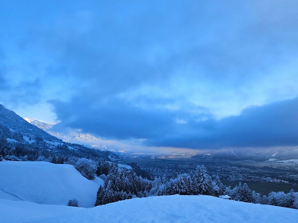 Ausblick vom Hof auf die verschneiten Berge und das Inntal.