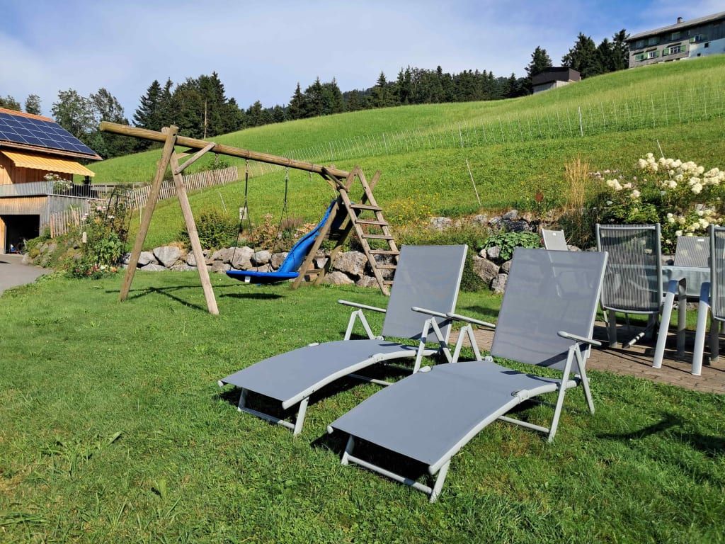 Der Garten des Bauernhofs bietet eine Schaukel, eine Rutsche, Sonnenliegen und eine Terrasse mit Sitzgelegenheiten.