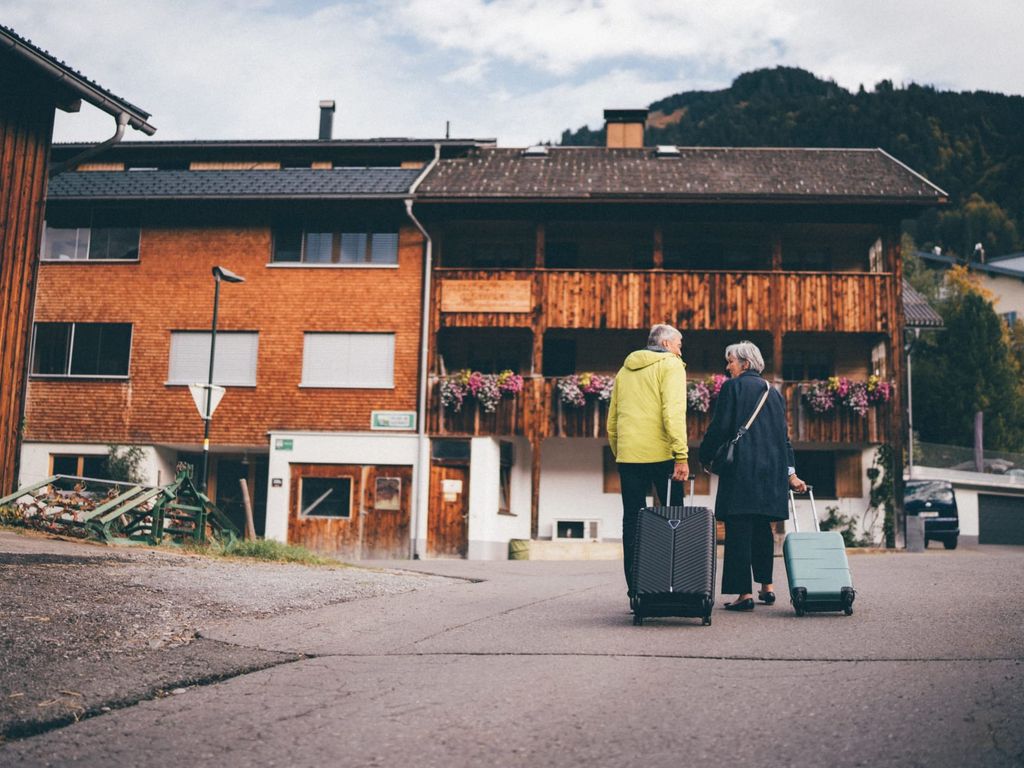 Gäste treffen mit ihrem Gepäck vor den Ferienwohnungen des Bauernhofs ein.