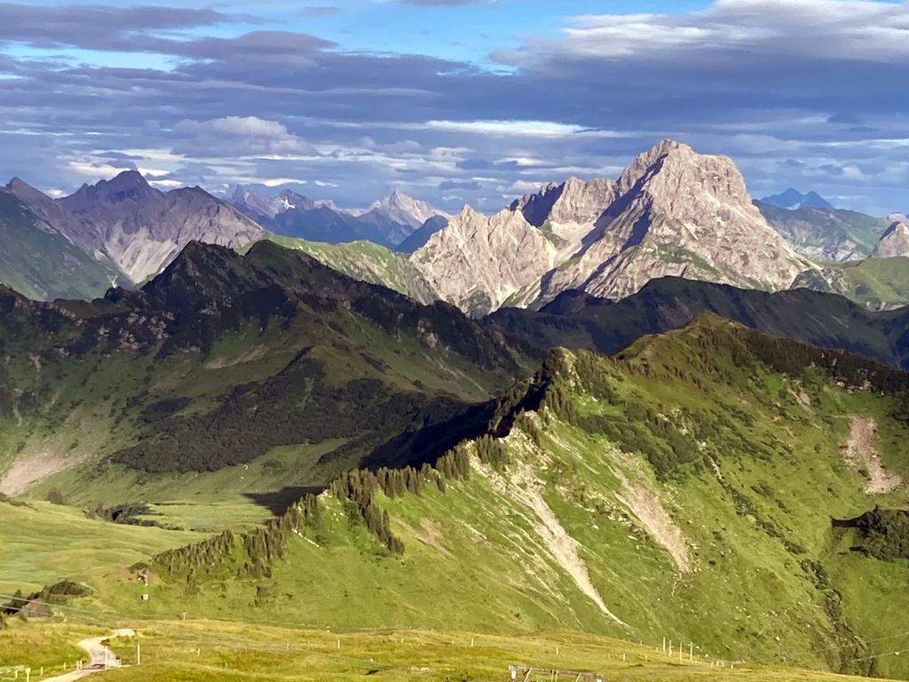 Blick auf die umliegende Bergwelt mit grünen Almwiesen und felsigen Gipfeln des Bauernhofs.
