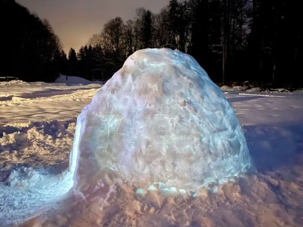 Ein stimmungsvoll beleuchtetes Iglu im verschneiten Außenbereich der Ferienwohnung bei Nacht.
