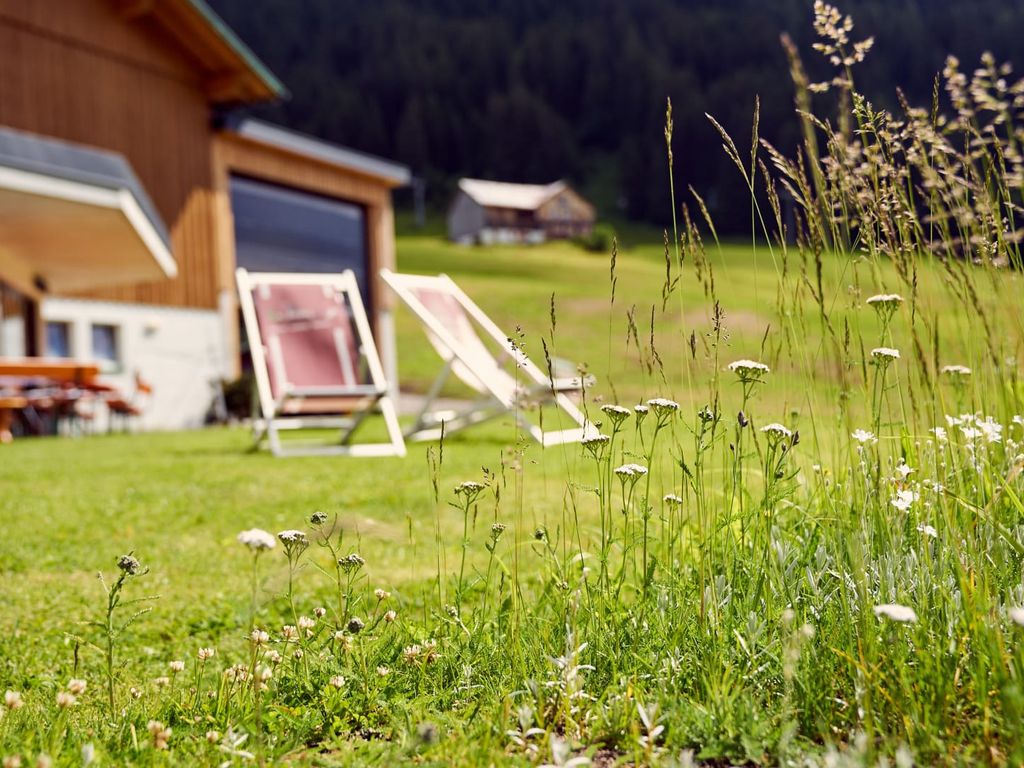 Die Außenanlage des Bauernhofs mit Liegestühlen auf der Rasenfläche und natürlicher Umgebung.