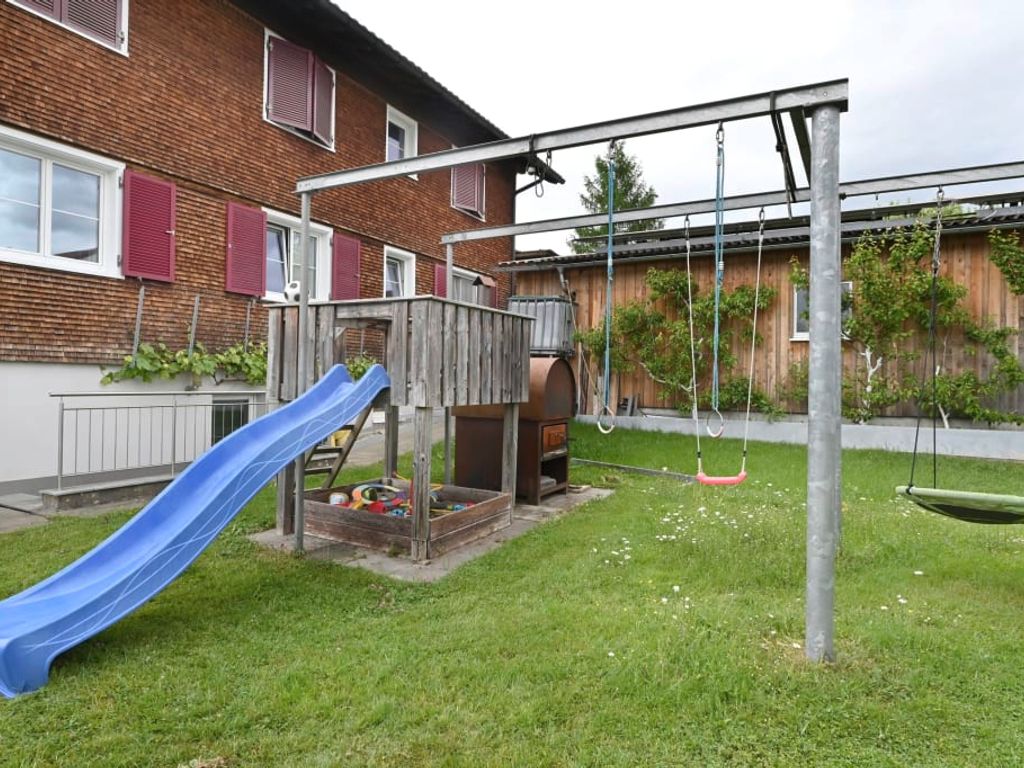 Der Kinderspielplatz am Hof mit Rutsche, Sandkasten und Schaukeln.