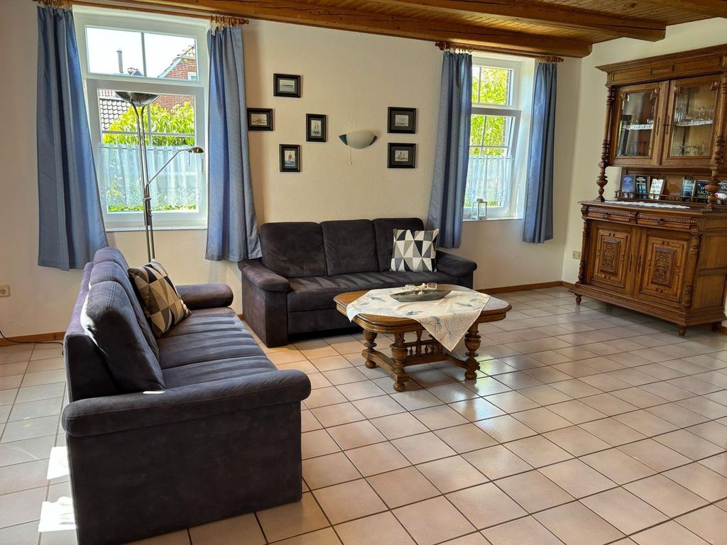 Wohnzimmer. Helles Wohnzimmer im Ferienhaus mit gemütlicher Sitzgruppe, rustikalem Buffetschrank und Deckenbalken für entspannte Urlaubstage.