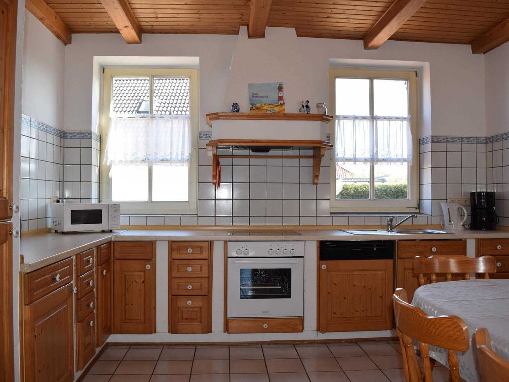Gemütliche, voll ausgestattete Landhaus-Küche in Ferienwohnung mit Holzdekor, modernen Geräten und hellen, lichtdurchfluteten Fenstern.