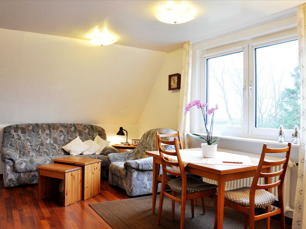 Im großen Wohnzimmer befindet sich eine gemütliche Couch und ein Esstisch.