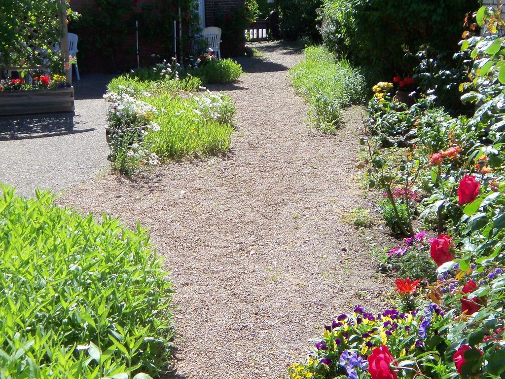 Blick in den Bunten Innenhof mit den Südterrassen. Vorn der Eingang zum Grundstück. Das Grundstück ist eingezäunt und wird nur von uns und unseren Gästen betreten.