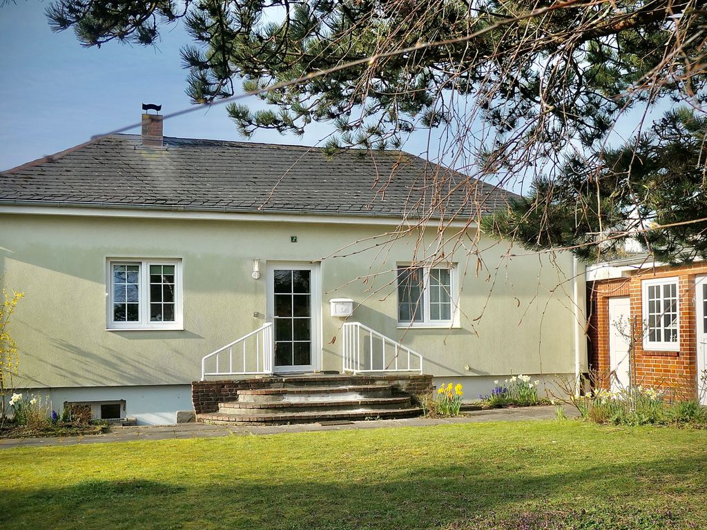 Eingangsbereich mit großzügigem Vorgarten und links kleinem Ziegelhaus