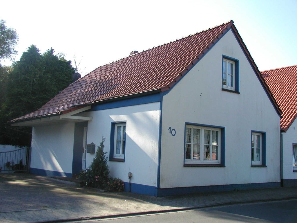 Fischerhaus. Gemütliches Ferienhaus in Hooksiel: Weißes Haus mit rotem Dach, privatem Stellplatz und hellem Ambiente für den Urlaub.