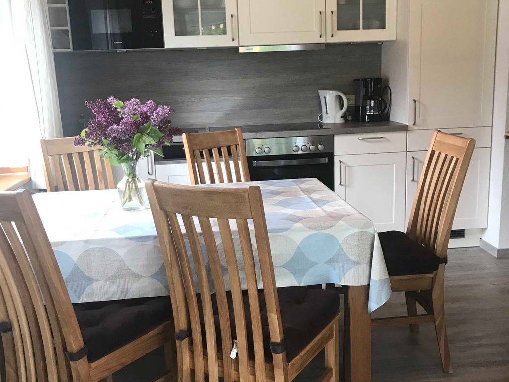 Küchenansicht Gemütliche Landhausküche im Ferienhaus mit weißen Schränken, rustikaler Holzdecke und einer einladenden Essgruppe für die ganze Familie.